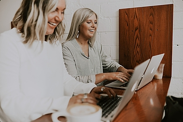 Two laughing women in front of a laptop
